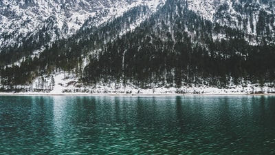 在水体附近被雪覆盖的山